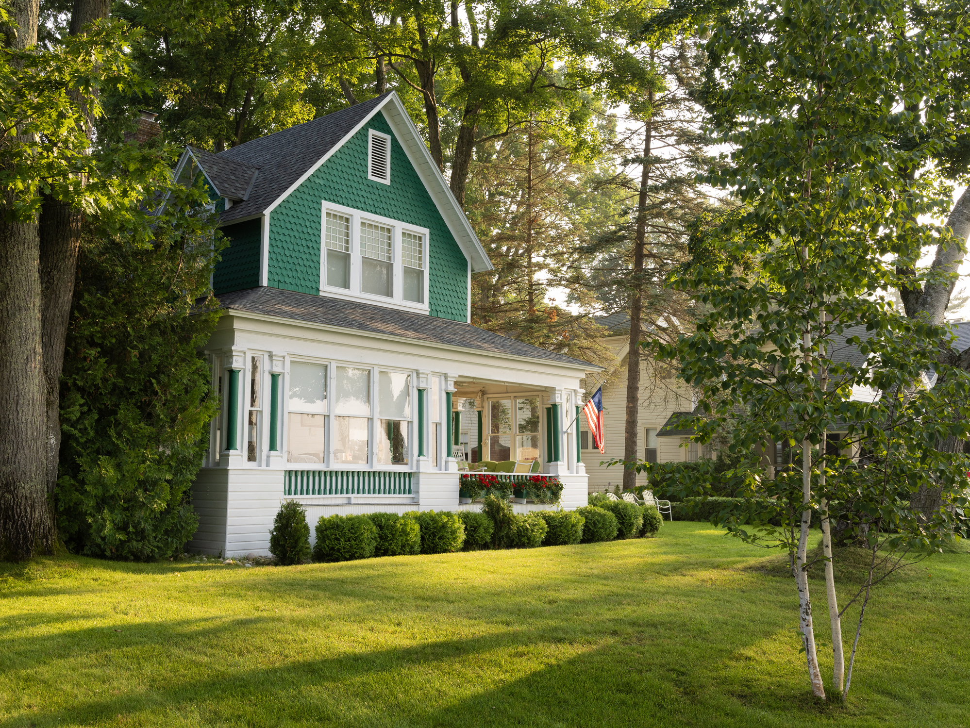 Green two-story house with porch, American flag