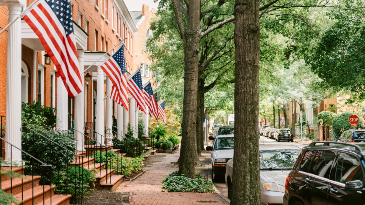 Street with American flags and parked cars.