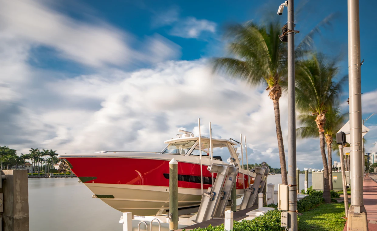 Red boat docked by palm trees and water.