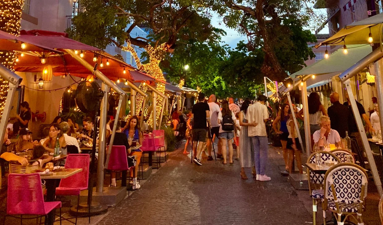 Bustling outdoor dining scene with string lights.