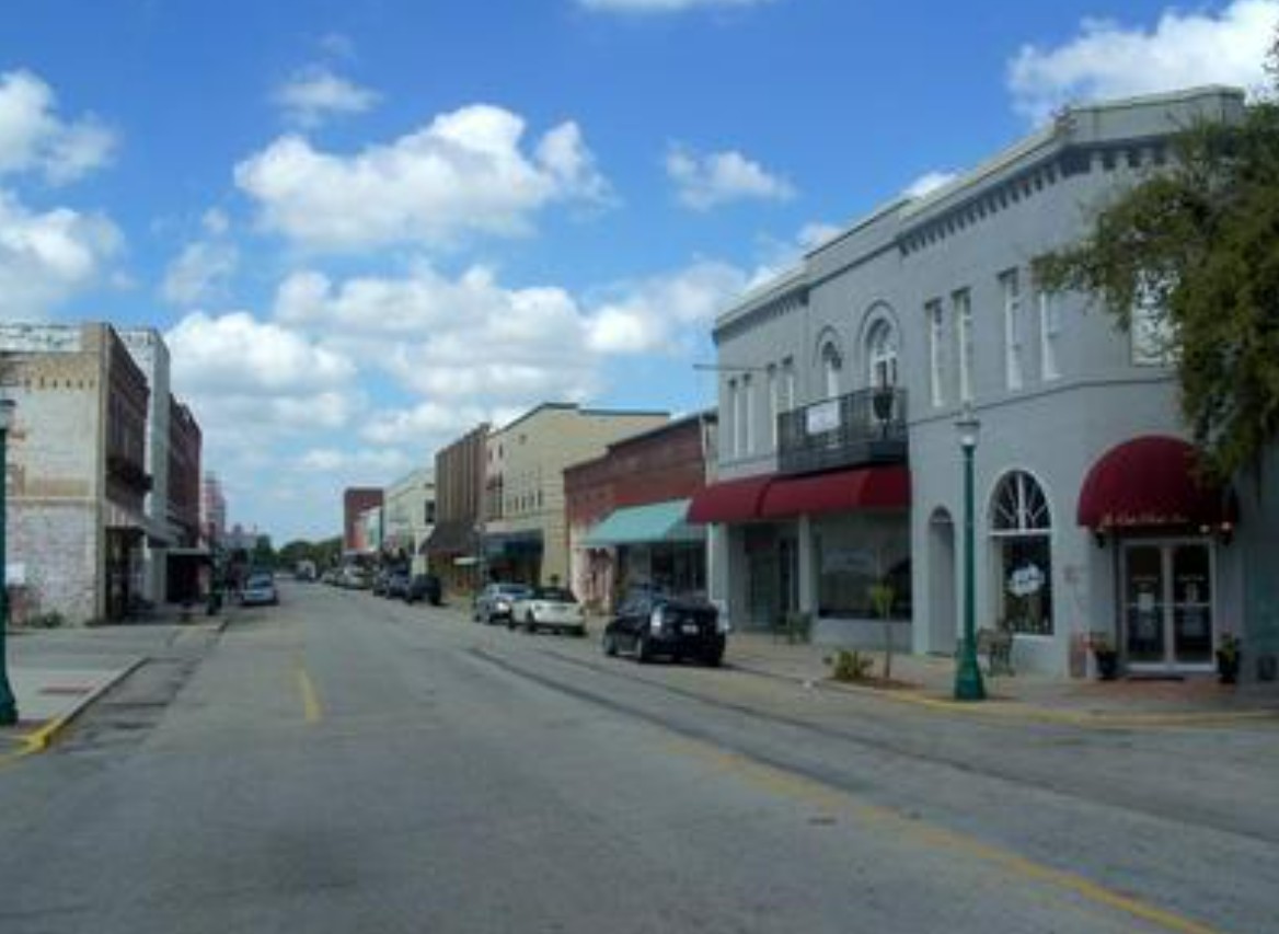 Small downtown street with storefronts and cars